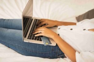 Personne faisant un achat en ligne sur un ordinateur portable, carte bancaire en main